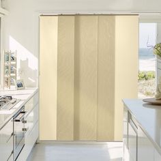 a kitchen with white cabinets and an open sliding door