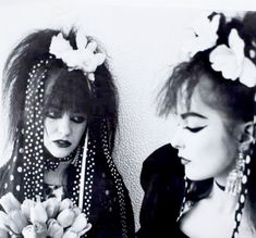 two young women with flower crowns on their heads, one holding a bouquet of flowers