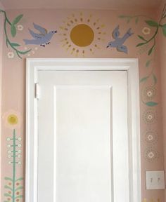 a white door sitting inside of a bathroom next to a wall with flowers and birds painted on it