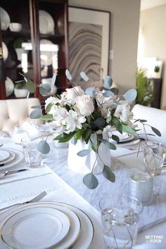 a table set with plates, silverware and flowers in a vase on top of it