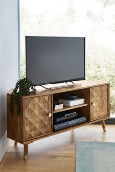 an entertainment center with a flat screen tv on it's stand in front of a window