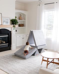 a toddler playing on an inflatable slide next to a fire place and fireplace