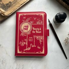 a red book sitting on top of a table next to a pen and ink roller