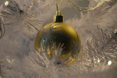 a yellow ornament hanging from a white christmas tree