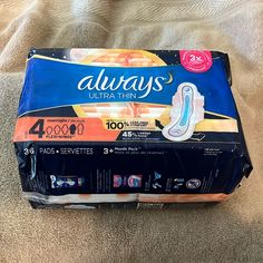 a box of alwayss ultra thin diapers on a bed