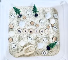 a white tray filled with wooden toys and snowflakes that spell out winter on it