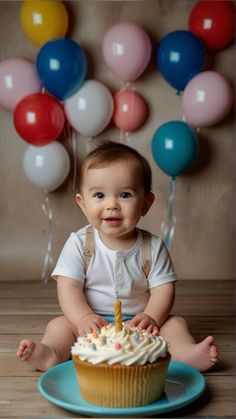 a baby sitting in front of a birthday cupcake