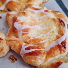 several pastries with white icing sitting on top of a piece of paper