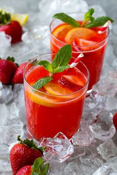 two glasses filled with red liquid and garnished with fresh strawberries on ice