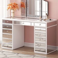 a white desk with drawers and a mirror on it in front of a pink wall