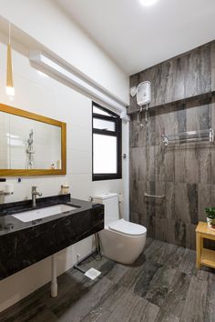 a modern bathroom with wood flooring and marble counter tops, along with a white toilet