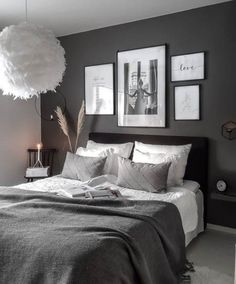 a bedroom with gray walls and pictures on the wall above the bed, along with a white fluffy ball hanging from the ceiling