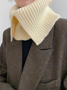 a woman wearing a white turtle neck sweater and brown jacket with her hands in her pockets