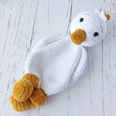 a knitted teddy bear laying on top of a white wooden floor