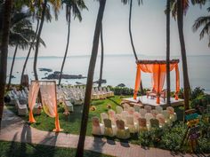 an outdoor wedding set up on the lawn with chairs and orange drapes, overlooking the ocean