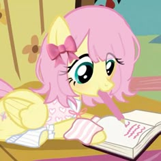 a pinkie is reading a book while laying on the floor in front of her