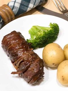 a white plate topped with meat, potatoes and broccoli next to a fork