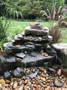 an outdoor fountain with rocks and water flowing from it's sides in a garden