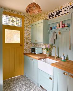 a kitchen with blue cabinets and yellow door, white sink and wooden countertop area