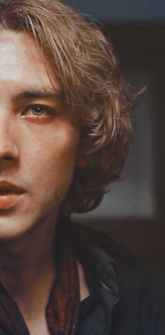 a young man with freckled hair and blue eyes looks at the camera while wearing a black shirt