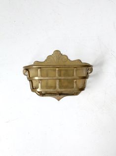 an antique brass wall mounted shelf against a white wall