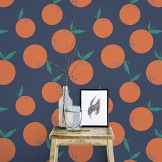 an orange wallpaper with leaves on it next to a small wooden table and vase