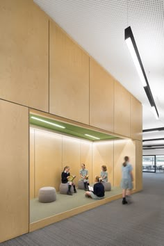 people are sitting on bean bags in an office setting with light wood walls and flooring