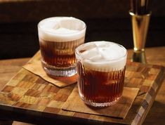 two glasses filled with liquid sitting on top of a wooden tray