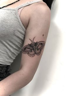 a woman's arm with a moth tattoo on the left side of her arm