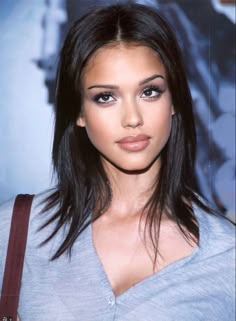 a close up of a woman with long hair and blue eyeshadow wearing a gray shirt