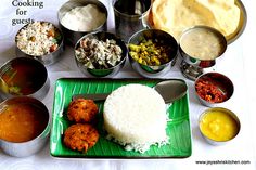 a green plate topped with lots of food next to bowls and sauces on a table