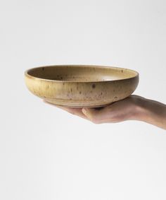 a person's hand holding a brown bowl on a white background with space for text