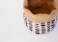 a black and white basket on a white surface with a brown cloth in the bottom