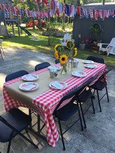 a table set up with plates and flowers on it for an outdoor party or gathering