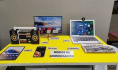 a yellow table topped with laptops and other electronic devices next to each other on display