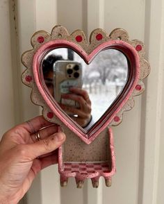 a person taking a selfie in front of a heart shaped mirror