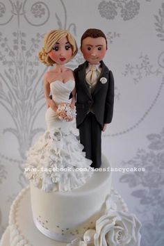 a bride and groom figurine on top of a wedding cake with white flowers