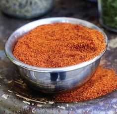 a metal bowl filled with spices on top of a table