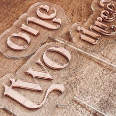 three glass signs with scissors on them sitting on top of a wooden table next to each other