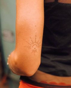 a woman's arm with a sun tattoo on the left side of her arm