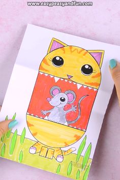 a child's hand holding up a drawing of a cat