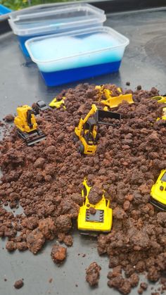 there are many toy construction vehicles in the dirt on top of some rocks and gravel