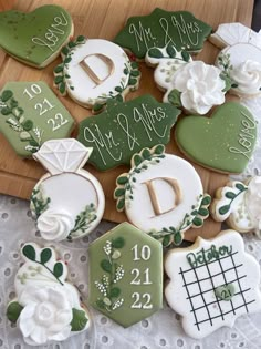 decorated cookies are arranged on a table with lace doily and greenery, including the letter d