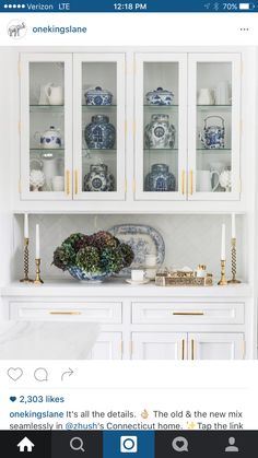 a kitchen with white cabinets and blue and white dishes on the counter top, along with gold trimmings