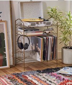 a record player sits on top of a metal rack next to a potted plant