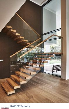 there is a wooden stair case in the house with glass railings on both sides