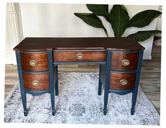 a desk with two drawers on top of it and a potted plant in the background