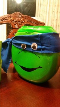 there is a green plastic ball with a face on it and a blue bow around its neck