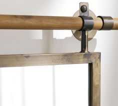 a close up of a metal and wood rail with a mirror in the back ground