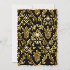 a black and gold greeting card with an ornate design on the front, featuring a diamond in the center